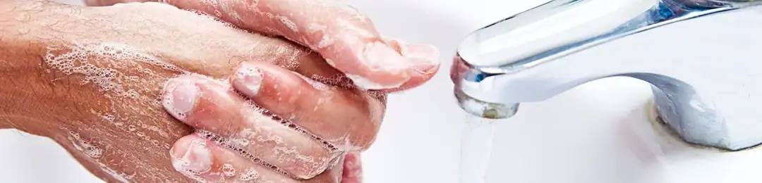 Hands being washed with soap under a running tap