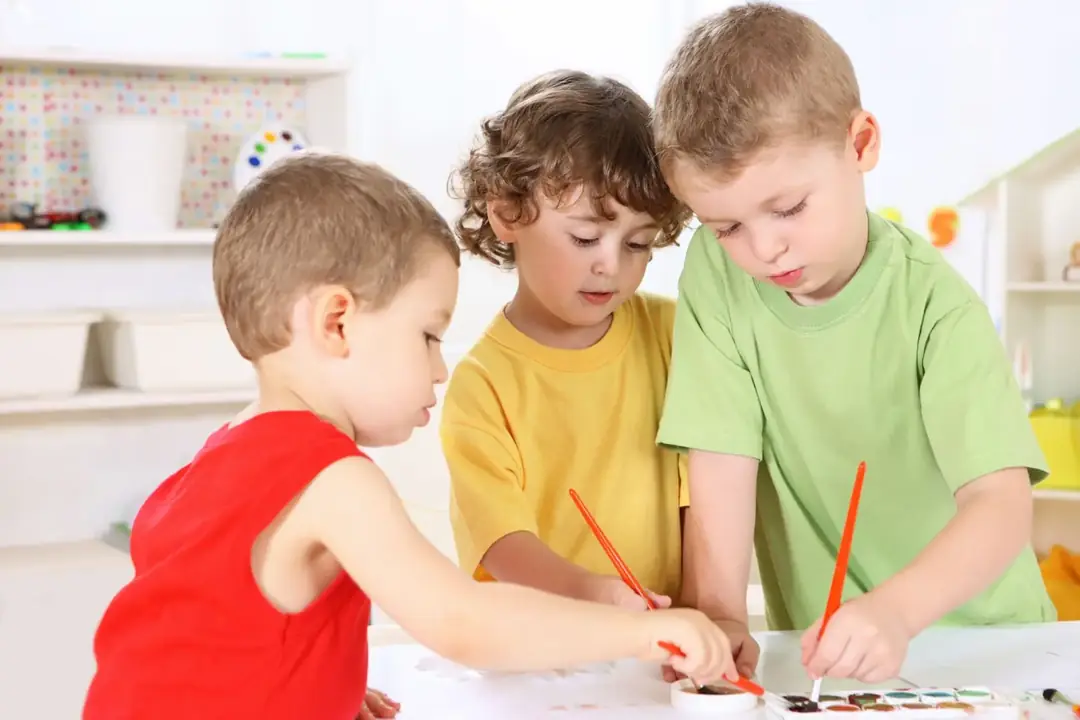 Three preschool boys painting together at an art table at Beehouse Nelson Ave. near Metrotown, Burnaby