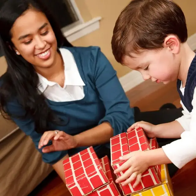Educator helping a young child build with large red brick blocks at Beehouse Hart St. in Coquitlam